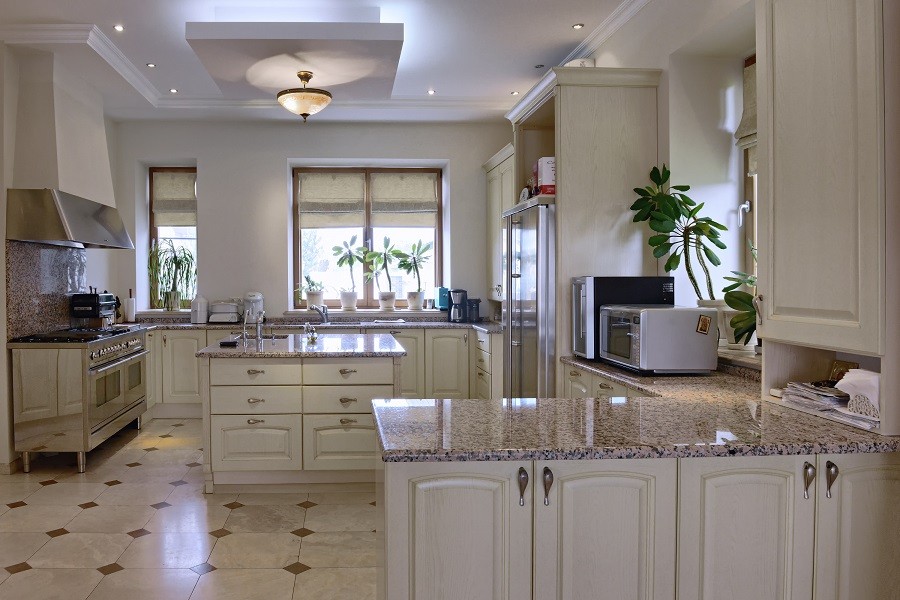 A modern kitchen featuring an island, stove, and motorized shades.