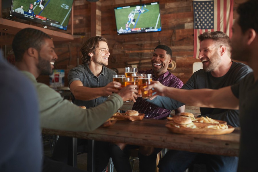 A group of men sitting around a table with beers in a bar setting.